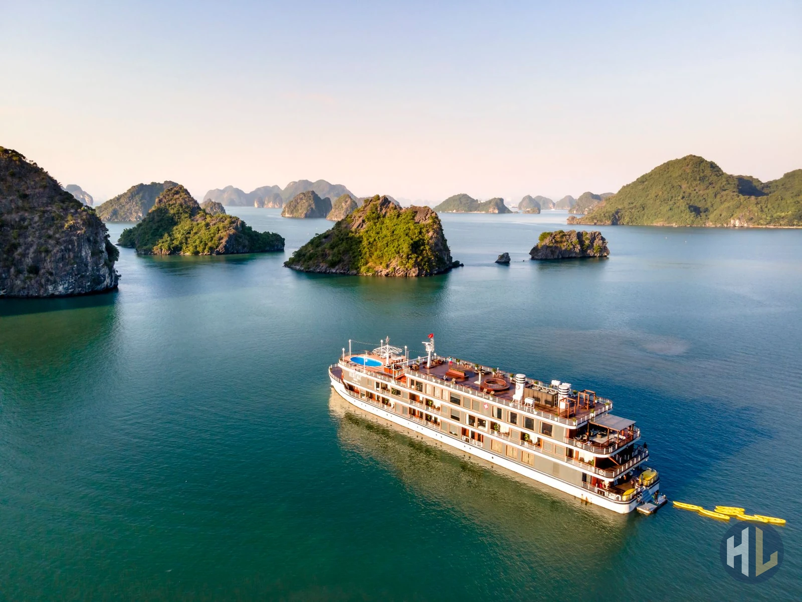 Du thuyền nhiều tầng sang trọng đang di chuyển trên vịnh biển xanh giữa các hòn đảo đá vôi kỳ vĩ. — hạ long travel